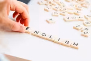 Lernen mit Leichtigkeit: spielerisch englische Vokabeln lernen: Es liegen viele Buchstaben als viereckige Plättchen auf einem weißen Tisch. Aus den Buchstaben wird das Wort English gebildet.